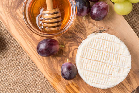 wooden board with cheese, grapes,and honeyの写真素材