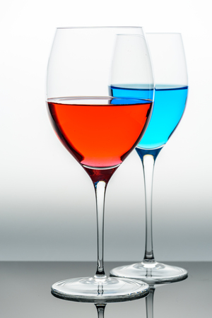 two glasses with blue colored water and red wineの写真素材