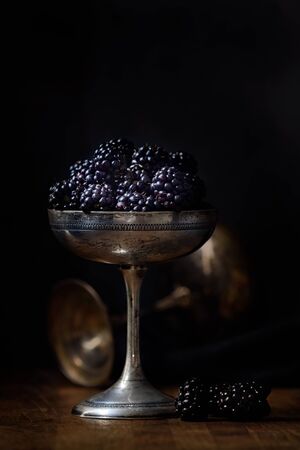 blackberries in a silver old cup in dark style food photographyの写真素材