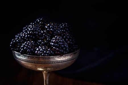 blackberries in a silver old cup in dark style food photographyの写真素材
