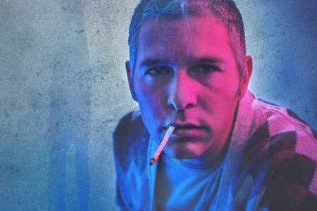 a man with cigarette in dramatic red and blue light