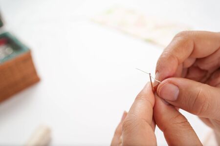 hands put thread on the needleの写真素材
