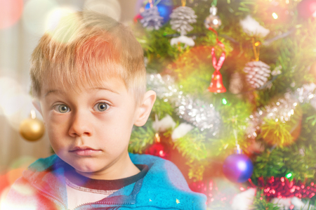 baby awaits Santa Claus with doubtful expression, seems to wonder: does it really exist?の写真素材