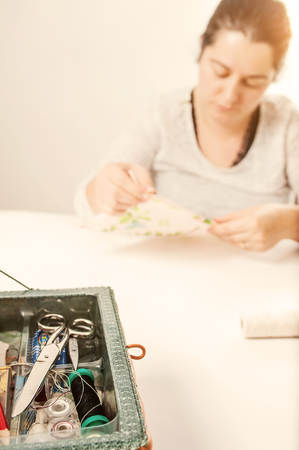 young woman stitches with needle and threadの写真素材