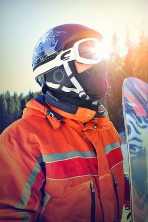 a snowboarder with helmet and mask studies the mountains, the sun is reflected on the same maskの写真素材