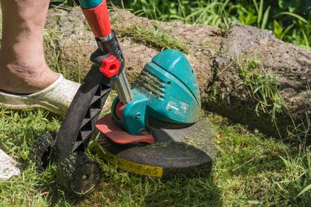 Man busy and concentrated trimming grass in the garden with brush cutter