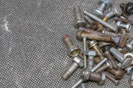 Several old screws on a grey texile background