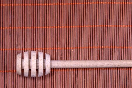 Wood Honey spoon on a nice wicker carpet as backgroundの写真素材