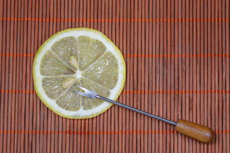 Sliced fresh lemon with forks on a nice wicker carpet as backgroundの写真素材