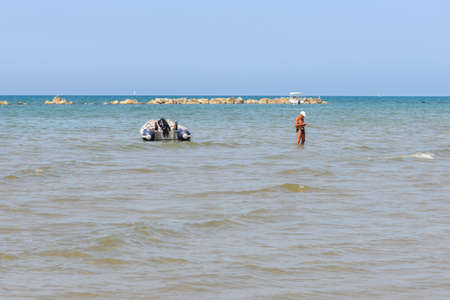 A senior man taking a bath in the mediterranean sea, near a boatの写真素材