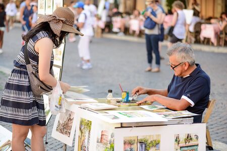 Rome, Italy - August 22, 2015: the famous Navona square a man selling pictures to a tourist girlのeditorial素材