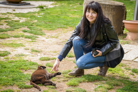 a girl playing in a garden with a black catの写真素材