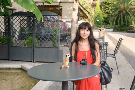 nice girl sitting on a chair at a little iron table with a puppet on itの写真素材