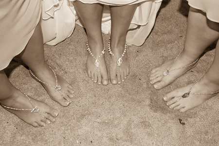 Three pair of feet wearing a jewel on the sandの写真素材