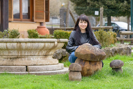 A girl posing and smiling behind a wood mushroom in a public parkの写真素材