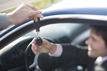 Businessman receiving car key of his new car, focus on the keyの写真素材