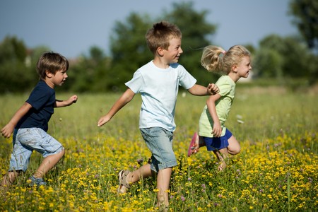 Three cute children running outdoorsの写真素材