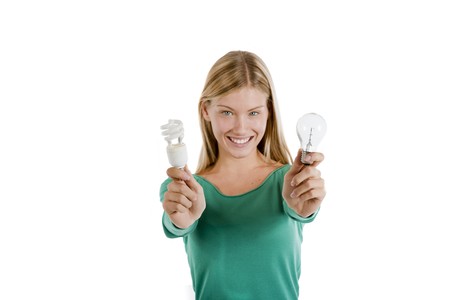 Teenage girl holding traditional and energy efficient light bulbs, isolated on white