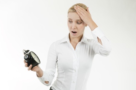 Businesswoman looking shocked at the clockの写真素材