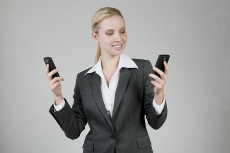 Businesswoman thinking about which mobile phone is betterの写真素材