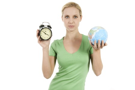 Young woman holding a wake up alarma and the Earth; concepts: time to wake up, time to protect the...