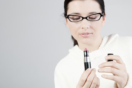 Close-up of a young woman applying lipstickの写真素材