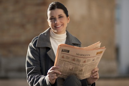 Young businesswoman reading newspaper outdoorsの写真素材