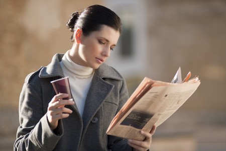 Young businesswoman taking a rest with newspaper and coffeeの写真素材