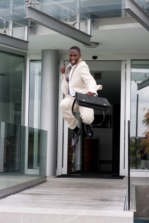 Businessman jumping of happiness outside his officeの写真素材