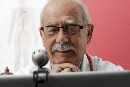 Senior doctor speaking with patient through webcam