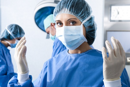 Portrait of a female surgeon, operation in the background