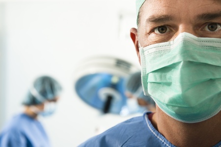 Portrait of a male surgeon at work, people in tha backgroundの写真素材