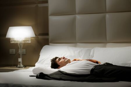 Tired Businessman resting in hotel roomの写真素材