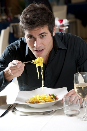 Man eating spaghetti with fish and vegetables Man eating spaghetti with fish and vegetables