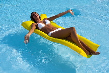 Happy Beautiful woman relaxing and floating on pool, high angle viewの写真素材