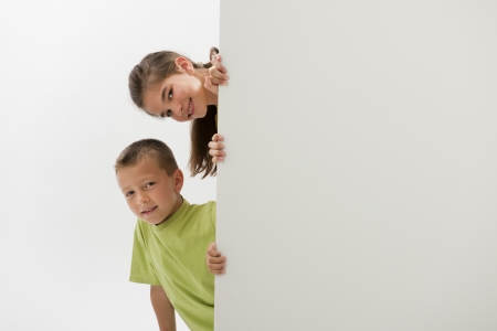 Two children holding a blank sign; you can add your own textの写真素材