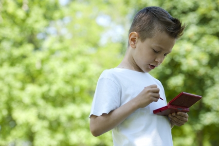 Little boy playing with is videogame outdoorsの写真素材