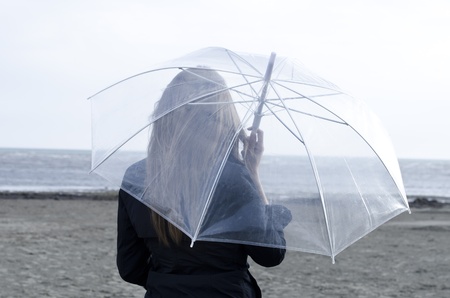 Young woman enjoying a rainy and windy day on the beachの写真素材