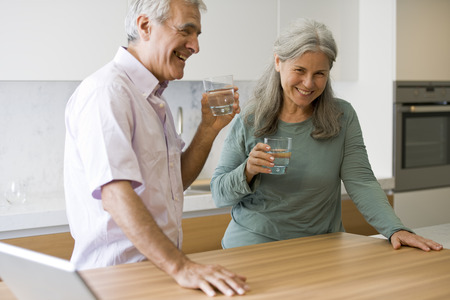 Senior couple drinking water in the kitchenの写真素材