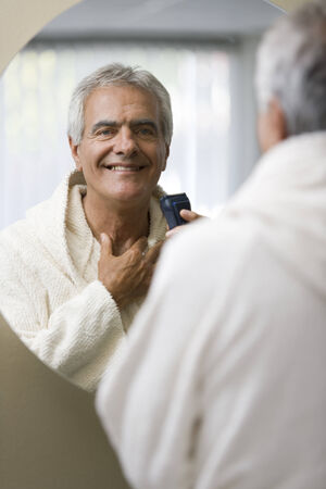 Senior happy man shaving his in front of the mirrorの写真素材