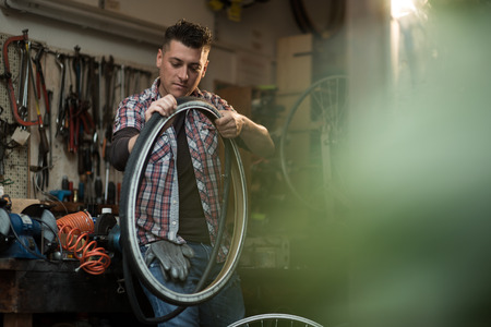 Young man working in a biking repair shopの写真素材