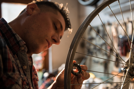 Young man working in a biking repair shopの写真素材