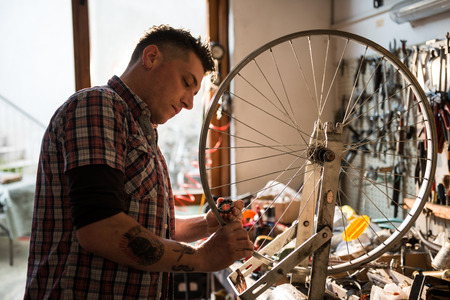 Young man working in a biking repair shopの写真素材