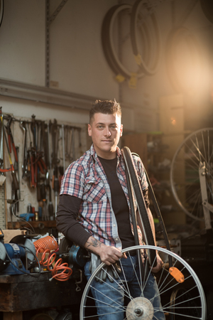 Young man working in a biking repair shopの写真素材