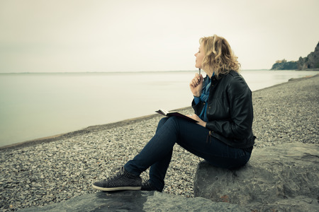 Woman writing her thoughts or poetry by the sea