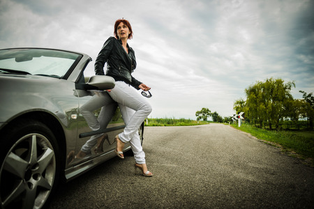 Woman posing next to her convertible carの写真素材