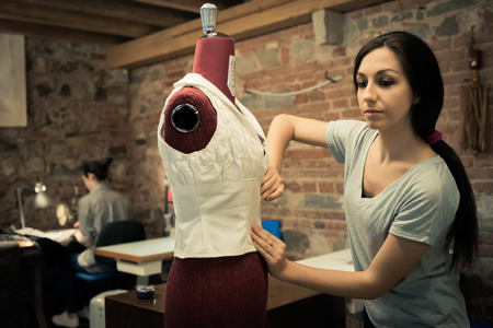 Young fashion designer pinning dress on mannequin