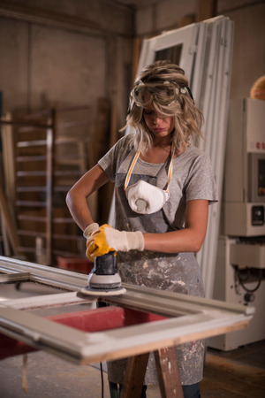 Female carpenter using power sanderの写真素材