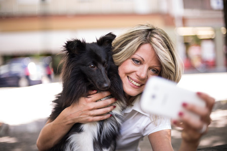 Young woman making a selfie with her dogの写真素材