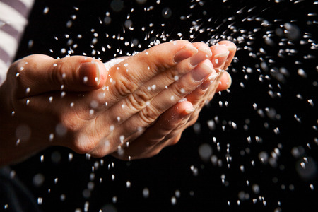 Sugar in hands blowing away on black backgroundの写真素材